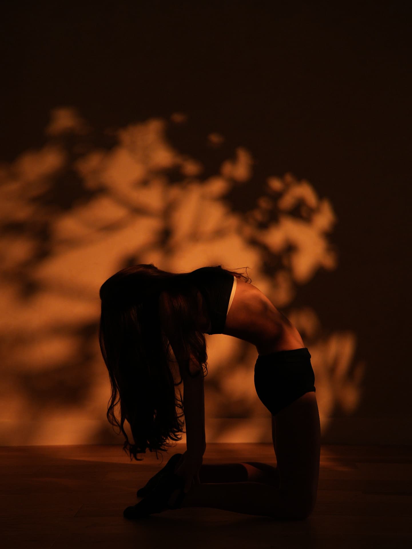 Yoga practitioner in a deep backbend with dramatic warm lighting